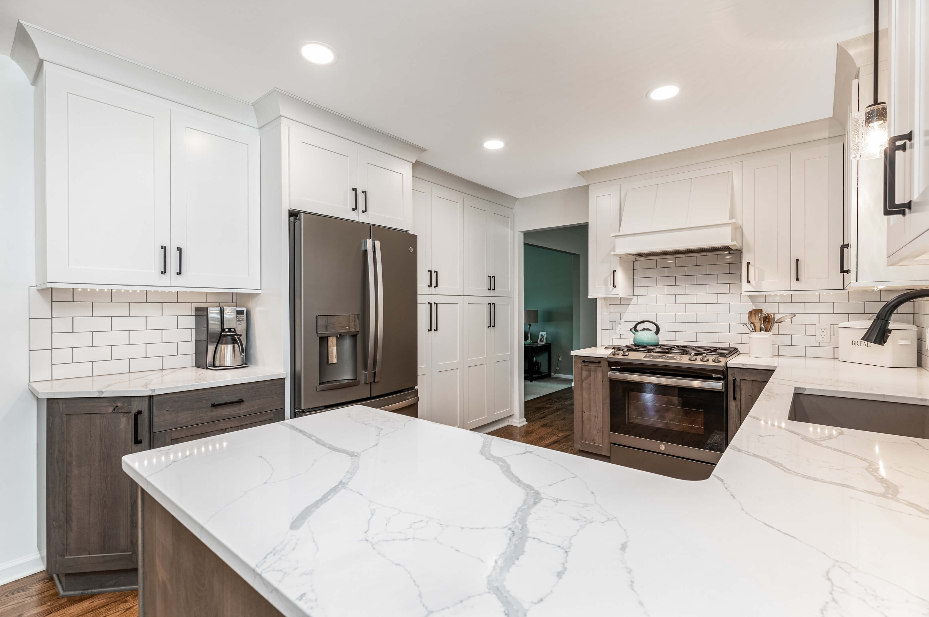 Unique white granite kitchen countertop with streaks of dark gray, lit from above with 2 contemporary glass lighting fixtures.