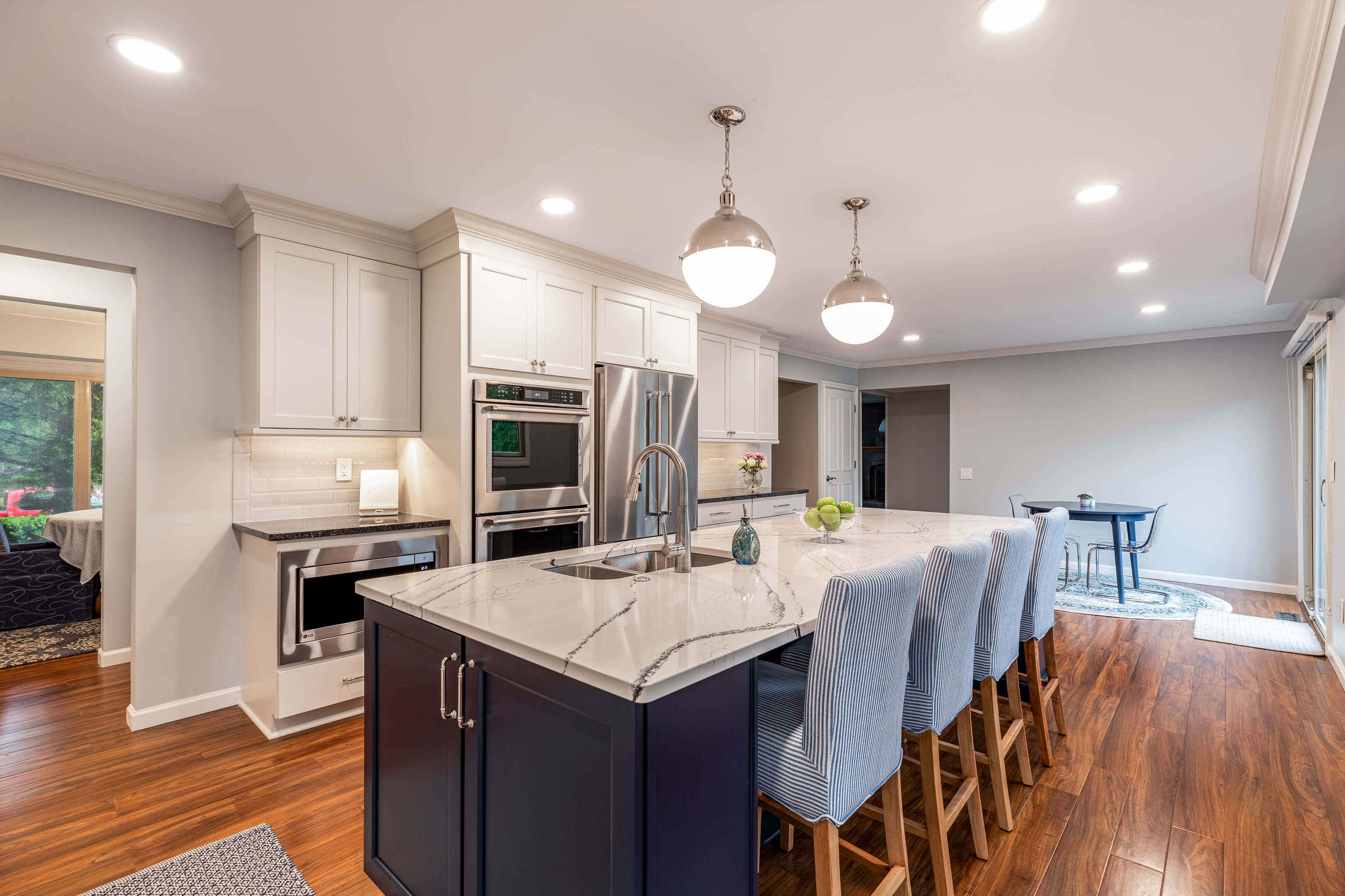 Unique white granite kitchen countertop with streaks of dark gray, lit from above with 2 contemporary glass lighting fixtures.